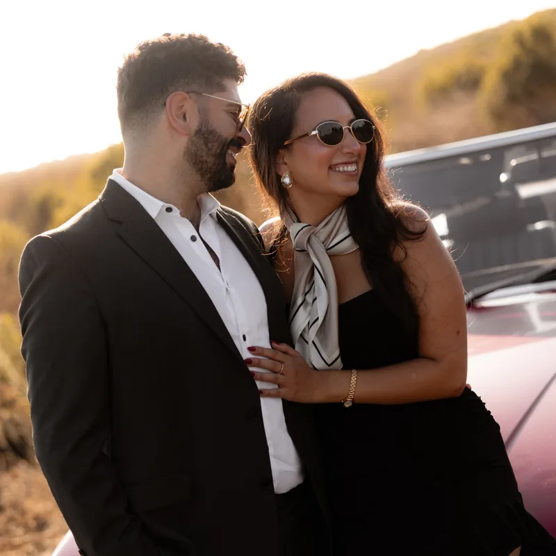 David and Joy laughing beside the convertible in golden-hour light